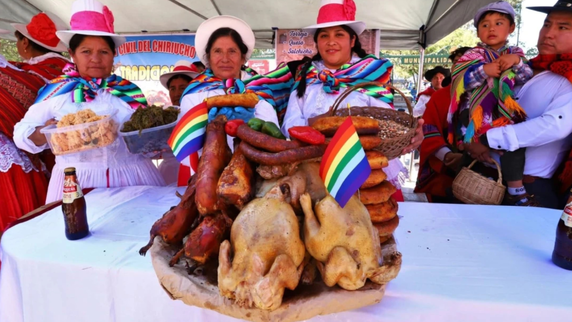 Andean women in traditional attire presenting a feast of roasted cuy (guinea pig), chicken, and sausages with Wiphala flags at a vibrant Andean food market - Magical Cusco Travel Agency.
