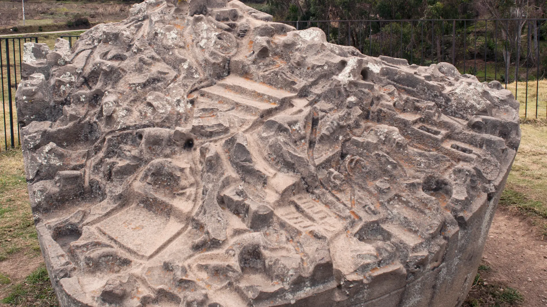 A large, intricate stone carving showing a topographical model or map of an ancient Inca site, revealing the detailed planning behind Inca Architecture. - Magical Cusco Travel Agency
